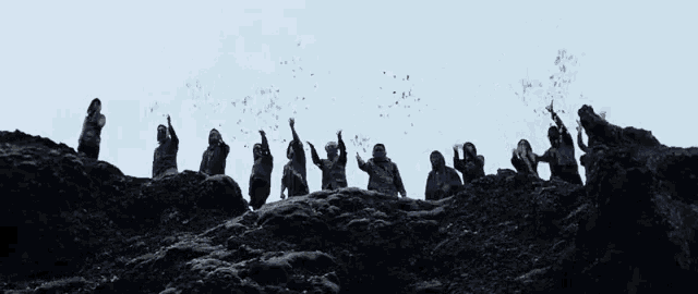 a group of people standing on top of a hill with their hands in the air