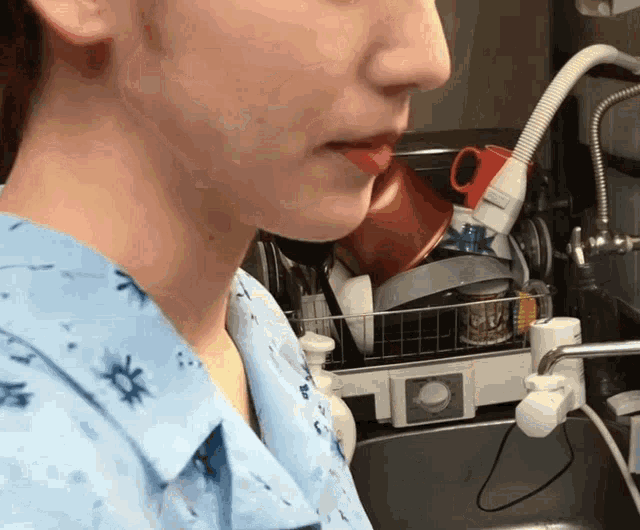 a woman standing in front of a sink with a hose attached to it