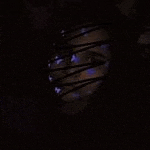 a close up of a person 's face in a dark room with a purple light coming out of it .