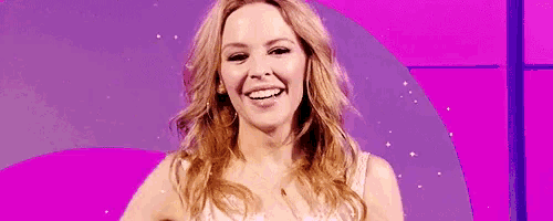 a woman with long hair is smiling in front of a pink background .