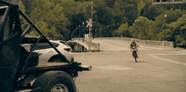 a person riding a motorcycle on a road with a railroad crossing sign in the background