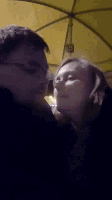 a man and a woman are kissing under an umbrella with a sign that says 52 on it