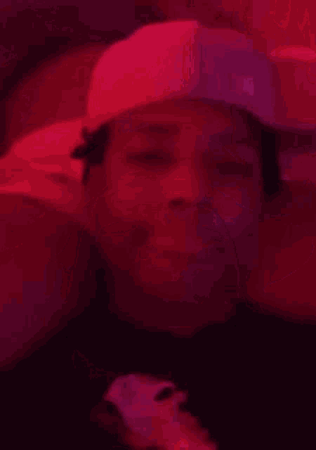 a man in a hat is smoking a cigarette in a dark room .