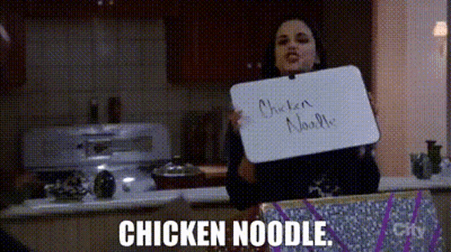 a woman is holding up a sign that says chicken noodle .