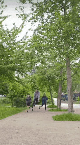 a group of people are running down a path surrounded by trees .