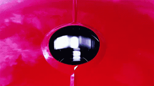 a man is driving a red sports car through a field