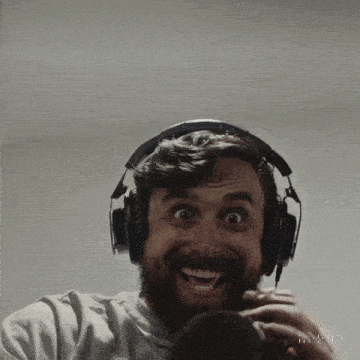 a man with a beard is wearing headphones and smiling at the camera