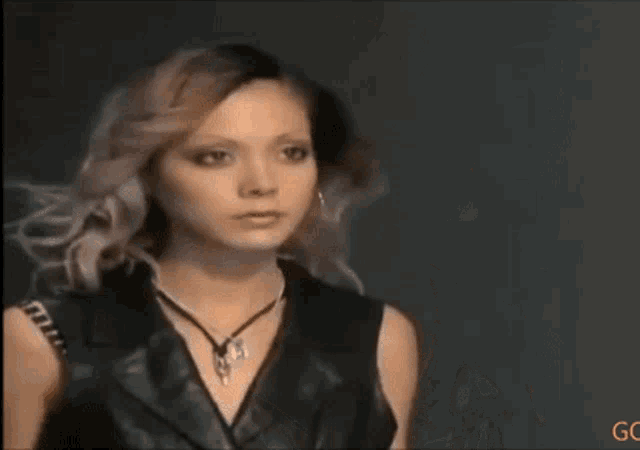 a woman wearing a black leather vest and a necklace