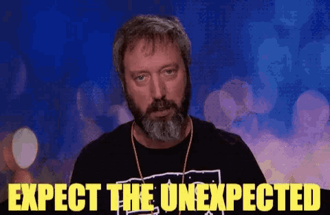 a man with a beard wearing a black shirt that says expect the unexpected