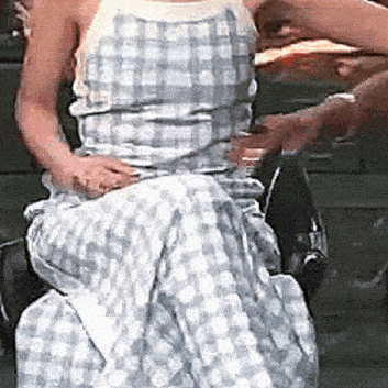 a woman in a plaid dress is sitting in a chair with a towel around her waist .