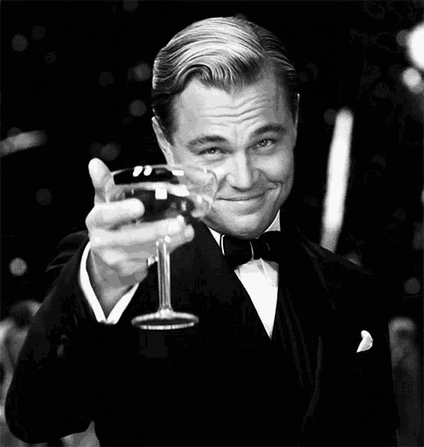 a man in a tuxedo is holding up a glass of wine