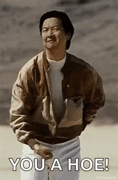 a man in a jacket is saying `` you a hoe '' while standing on a beach .