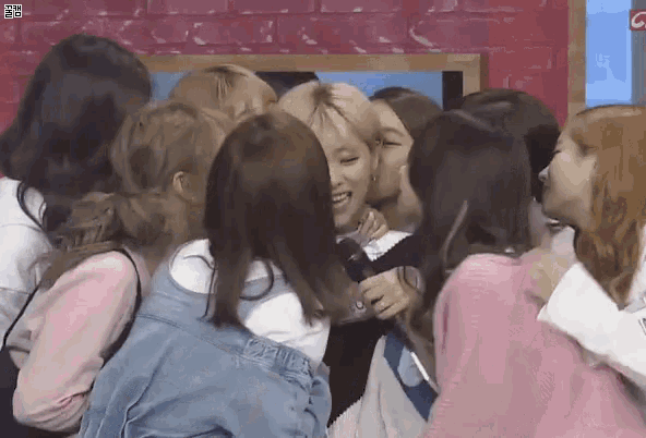 a group of girls are hugging each other and one girl is kissing another girl on the cheek