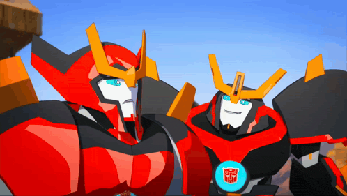 two transformers are standing next to each other and one has a transformers logo on his chest