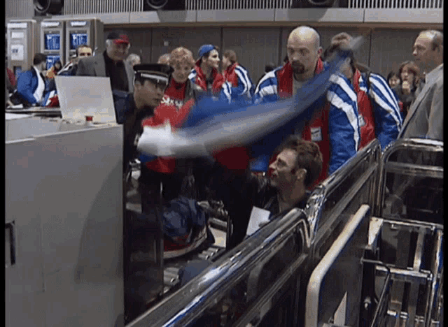a man in a red and blue jacket with the word stan on it is being searched