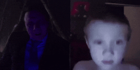 a man in a suit and tie is standing next to a little boy who is crying .