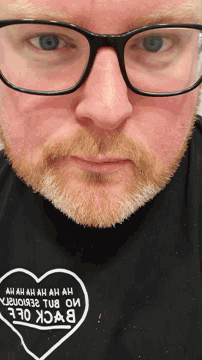 a close up of a man wearing glasses and a black shirt that says ' back ole ' on it
