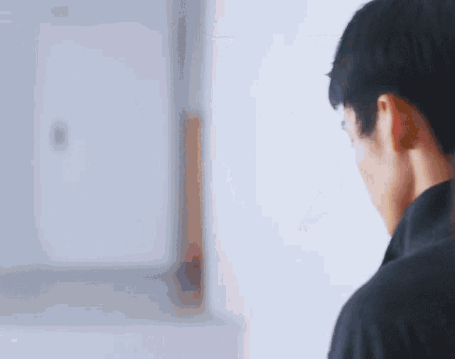 a man in a black shirt is standing in front of a mirror .