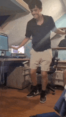 a man in shorts is dancing in front of a desk