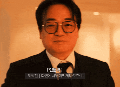 a man wearing glasses and a suit talks in korean