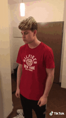 a man wearing a red t-shirt that says hilfiger new york