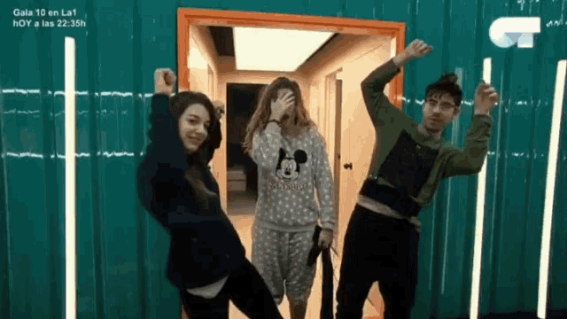 a woman in a mickey mouse pajama is standing next to two other people