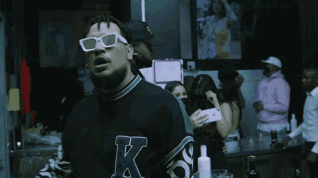 a man wearing sunglasses and a sweatshirt with the letter k on it