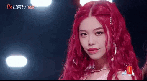a woman with long red hair is standing in front of a stage .