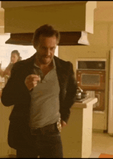 a man in a suit is standing in a kitchen holding something