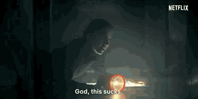 a woman is holding a light in a dark room and saying `` god , this sucks . ''