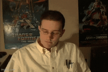 a man in a white shirt stands in front of a transformers poster