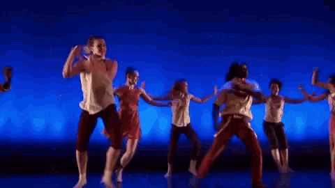 a group of people are dancing in front of a blue background