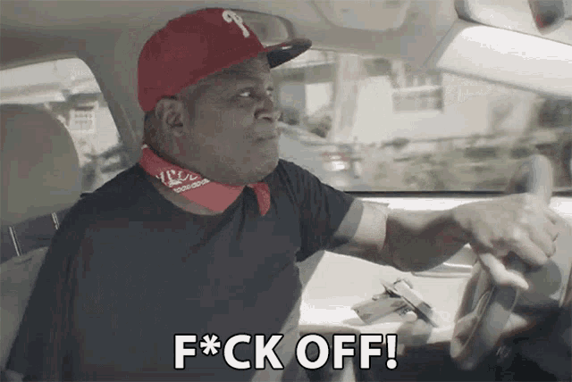 a man in a red hat is driving a car and says f*ck off
