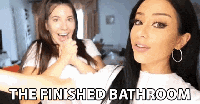two women are standing next to each other in a bathroom with the words `` the finished bathroom '' written on the bottom .