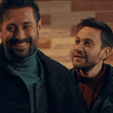 a man with a beard is smiling next to another man