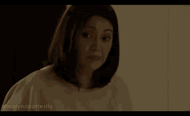 a woman in a white robe is standing in a dark room looking at something .