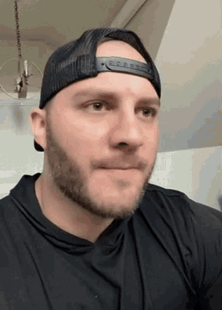 a man with a beard wearing a hat and a black shirt