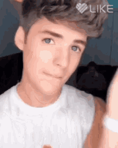 a young man in a white shirt is giving a thumbs up