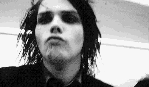 a black and white photo of a man in a suit and tie making a face .