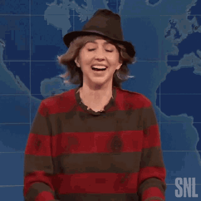 a woman wearing a hat and a striped sweater is dancing on a stage .