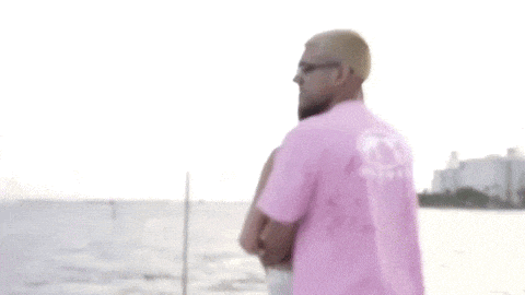a man and a woman are hugging each other on a boat . the woman is wearing a pink shirt .