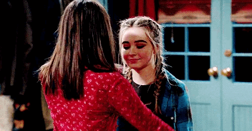 two girls are standing next to each other in front of a door .