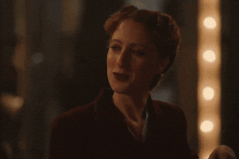 a woman in a red jacket is standing in front of a row of lights