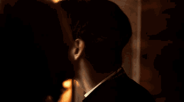 a close up of a young man 's face in a dark room with a lamp in the background .