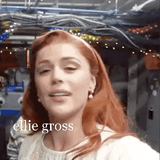 a woman with red hair is taking a selfie with a headband and earrings .