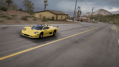 a yellow sports car is driving on a road