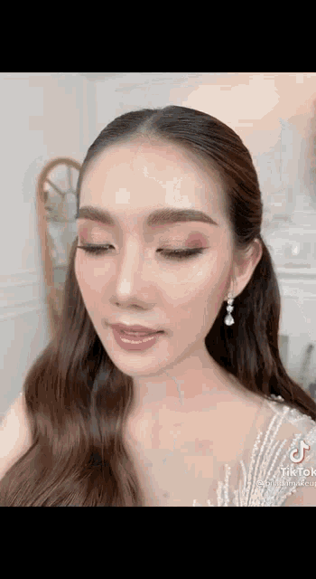 a close up of a woman 's face with a ponytail and earrings .