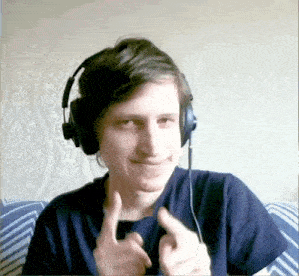 a young man wearing headphones is sitting on a couch and giving a thumbs up .