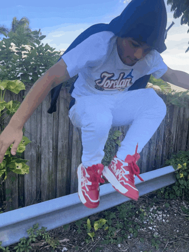 a person wearing a jordan shirt and white pants