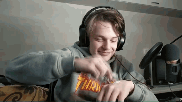 a man wearing headphones and a sweatshirt that says thrasher